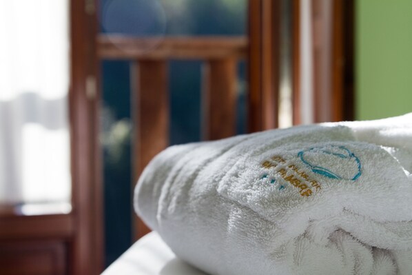 Una toalla blanca con texto bordado y un logotipo azul, sobre una superficie con una ventana al fondo.