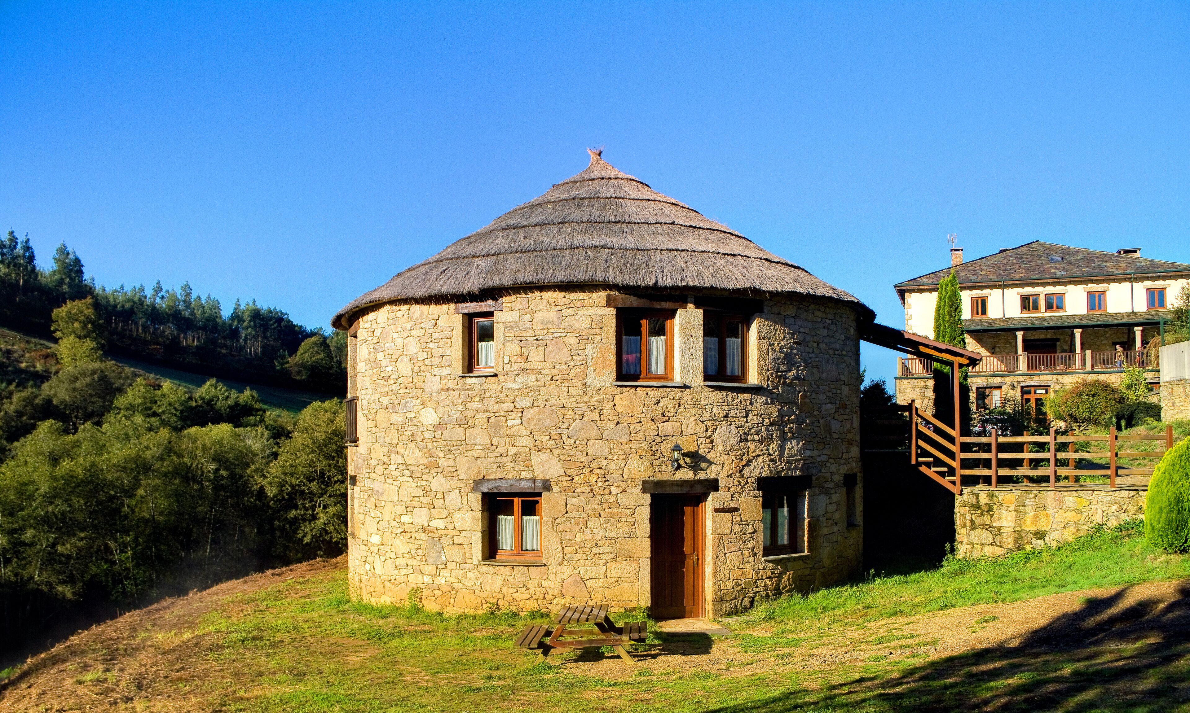 Un edificio de piedra con techo de paja, una puerta de madera y un pequeño porche.