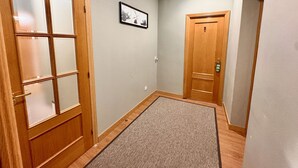 A hallway with wooden doors, a doormat, and a framed picture on the wall. - CH Rayuela (Madrid)
