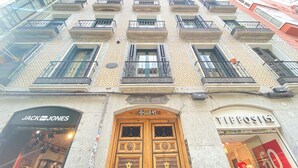 A building with a tiled facade, multiple balconies, and a prominent wooden door with a sign above it. - CH Rayuela (Madrid)