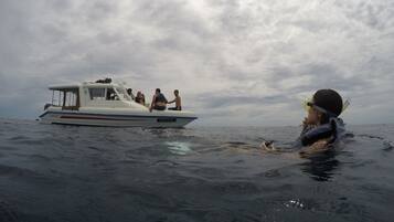 Un bote con pasajeros y una persona nadando cerca.