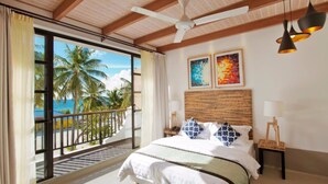 A hotel room with a balcony, a bed with white bedding, two paintings on the wall, and a ceiling fan. - Crystal Sands (Maafushi)