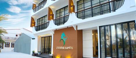 Un hôtel à la façade blanche, doté de nombreux balcons, et dont le logo porte l’inscription « Crystal Sands ».