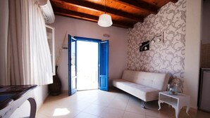 Une pièce avec un canapé blanc, une petite table d’appoint blanche, un rideau blanc, un plafond en bois et un mur à motifs.