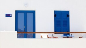 Un bâtiment blanc avec deux portes bleues et une petite table entourée de chaises devant.