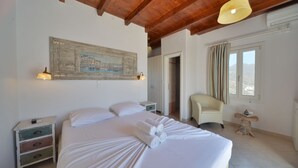 Une chambre à coucher avec un grand lit, une table de chevet, une chaise, une table en bois et un tableau accroché au mur.