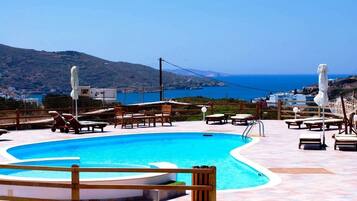 Una piscina al aire libre, sombrillas, tumbonas