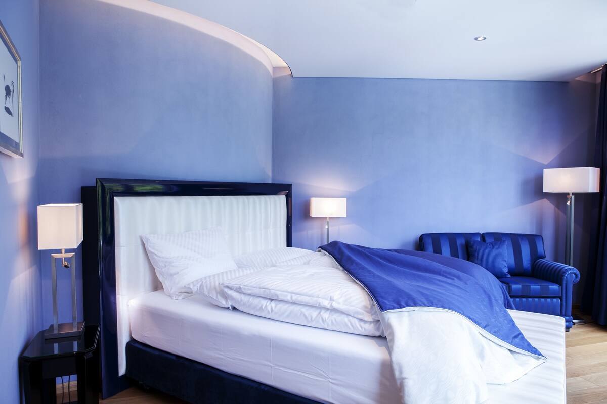 Une chambre d’hôtel avec un lit, une chaise et deux lampes de chevet.