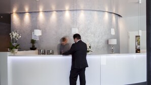 Un comptoir d’accueil moderne au design incurvé, avec un plateau blanc et une plante en pot.
