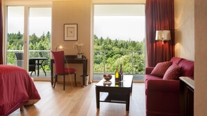 Une chambre d’hôtel avec un balcon, une table à manger, un canapé et un bureau.