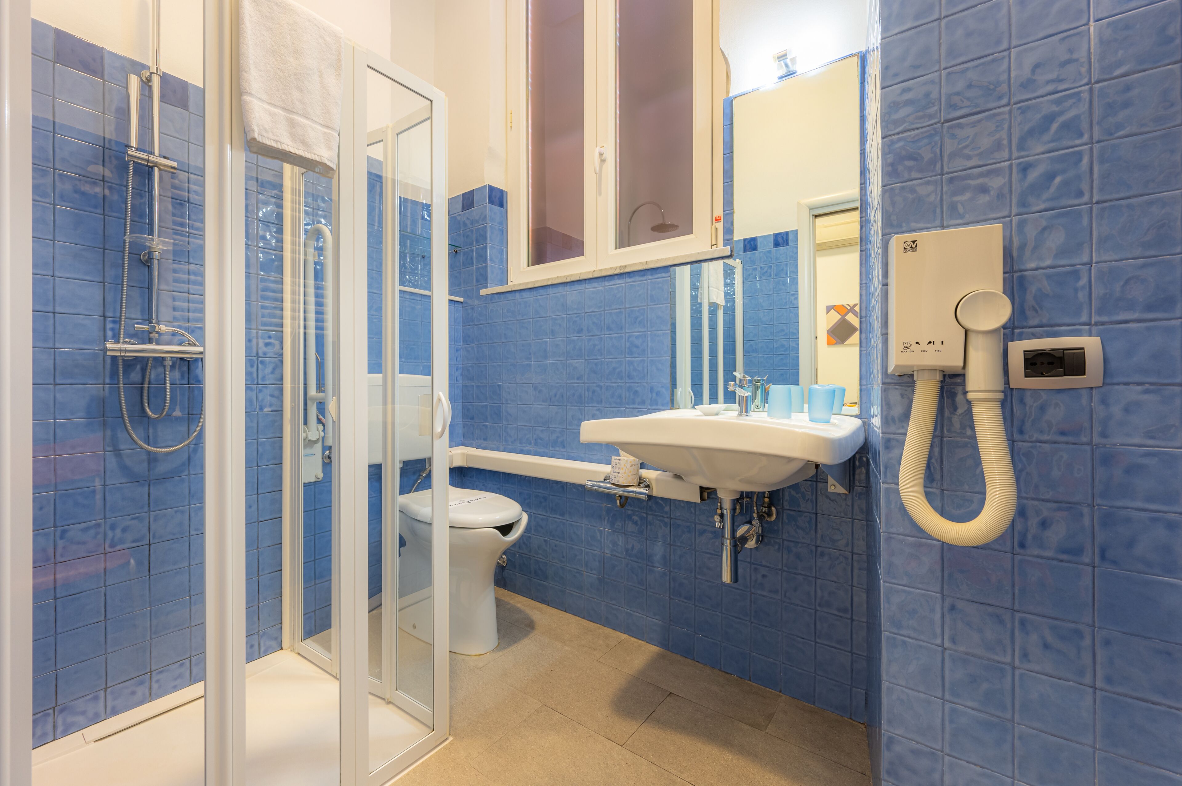 A bathroom with a glass-enclosed shower, a toilet, and a sink with a mirror above it.