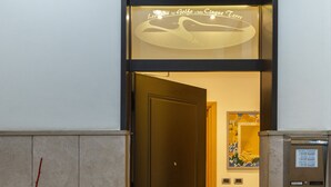 A hotel entrance with a dark wooden door, a tiled floor with a welcome mat, and a wall-mounted sign. - Affittacamere del Golfo e delle Cinque Terre (La Spezia)