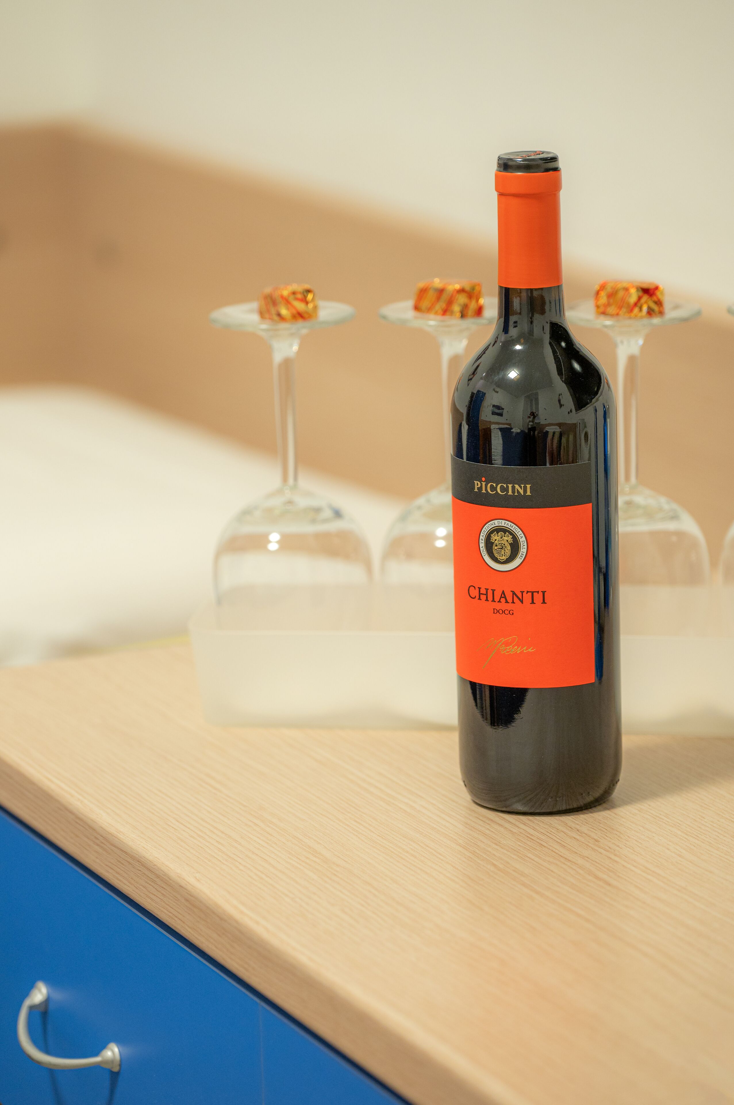 Een fles Chianti DOCG wijn op een houten ondergrond, met twee wijnglazen op de achtergrond.