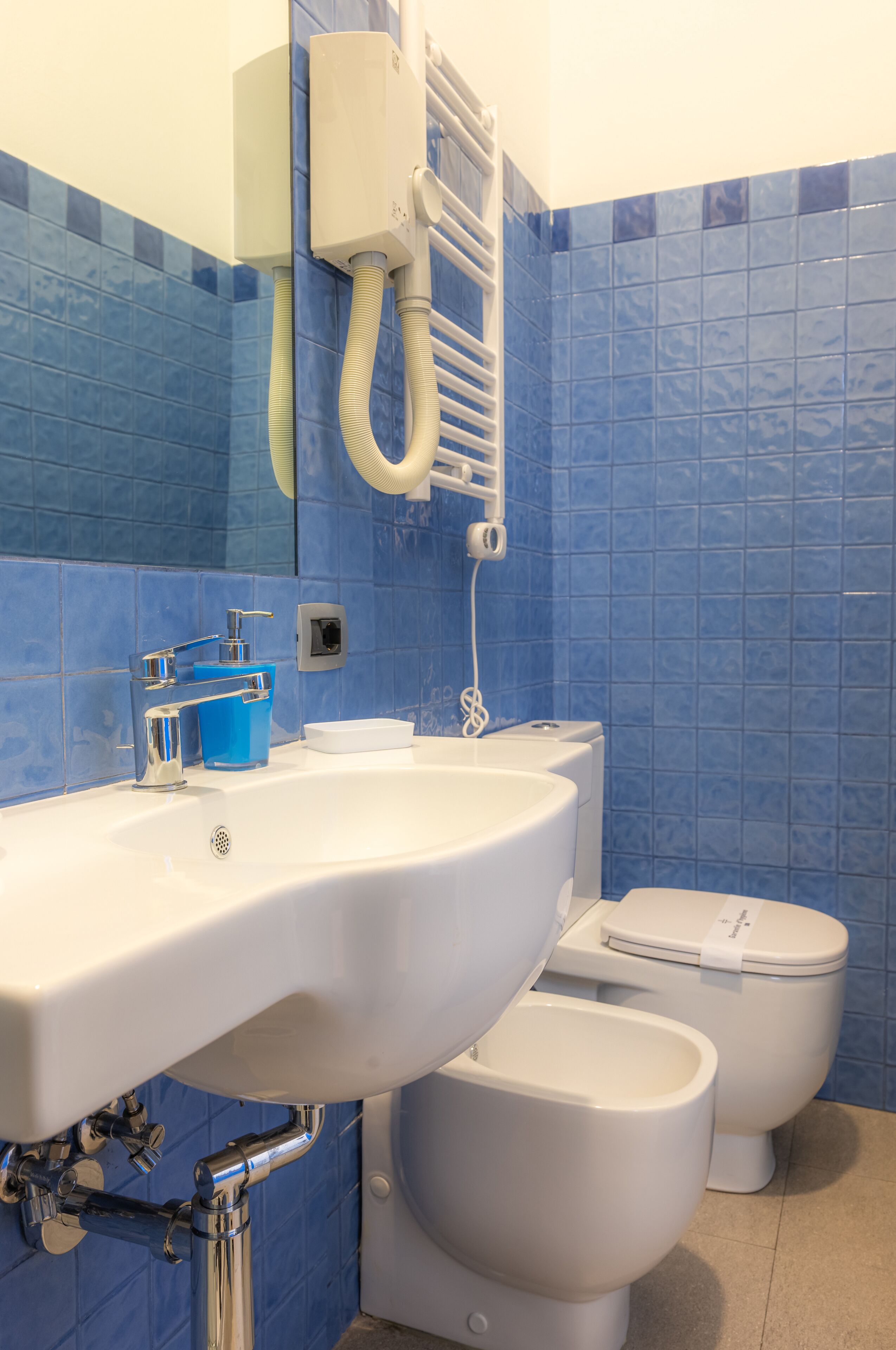 Un baño con un lavamanos, un inodoro y un bidé, todos en color blanco.