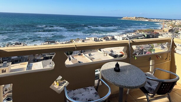 A balcony with a view of the sea, two chairs, and a table. - Eliza Apartments (Rethymno)