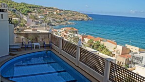 A rooftop swimming pool with a view of the sea and a town in the background. - Eliza Apartments (Rethymno)