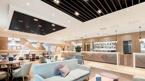 A modern hotel lobby with seating areas, a reception desk, and a bar. - Peter Scott House, Birmingham (Birmingham)