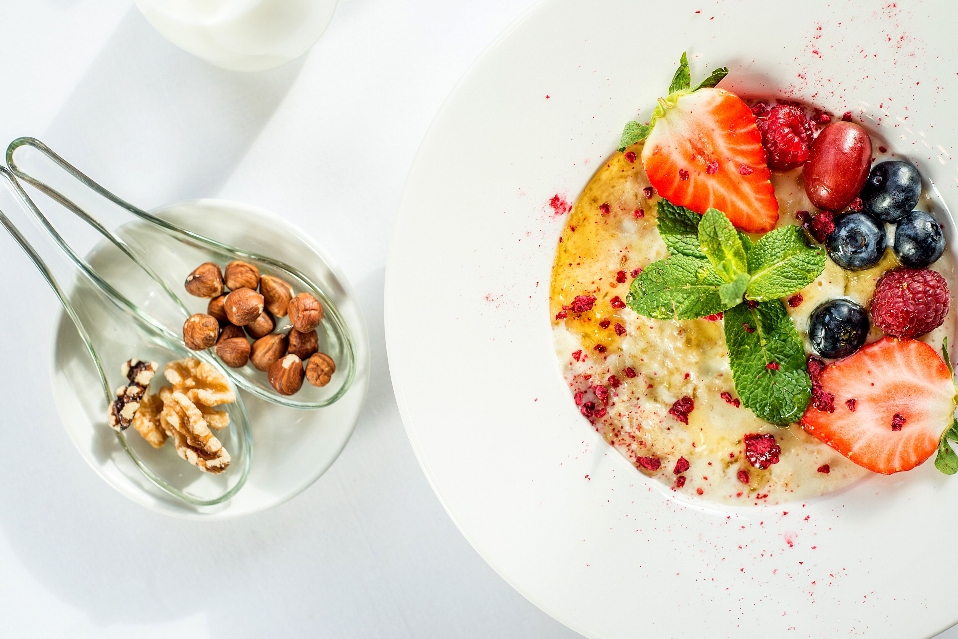 A white plate with a dessert topped with strawberries, blueberries, raspberries, and mint leaves.