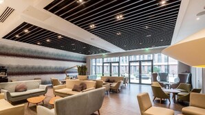 A spacious lobby with modern furniture, large windows, and a unique ceiling design. - Peter Scott House, Birmingham (Birmingham)