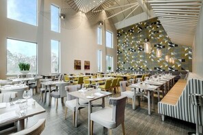 A modern restaurant with high ceilings, large windows, and a patterned wall. Tables are neatly arranged with chairs. - Peter Scott House, Birmingham (Birmingham)