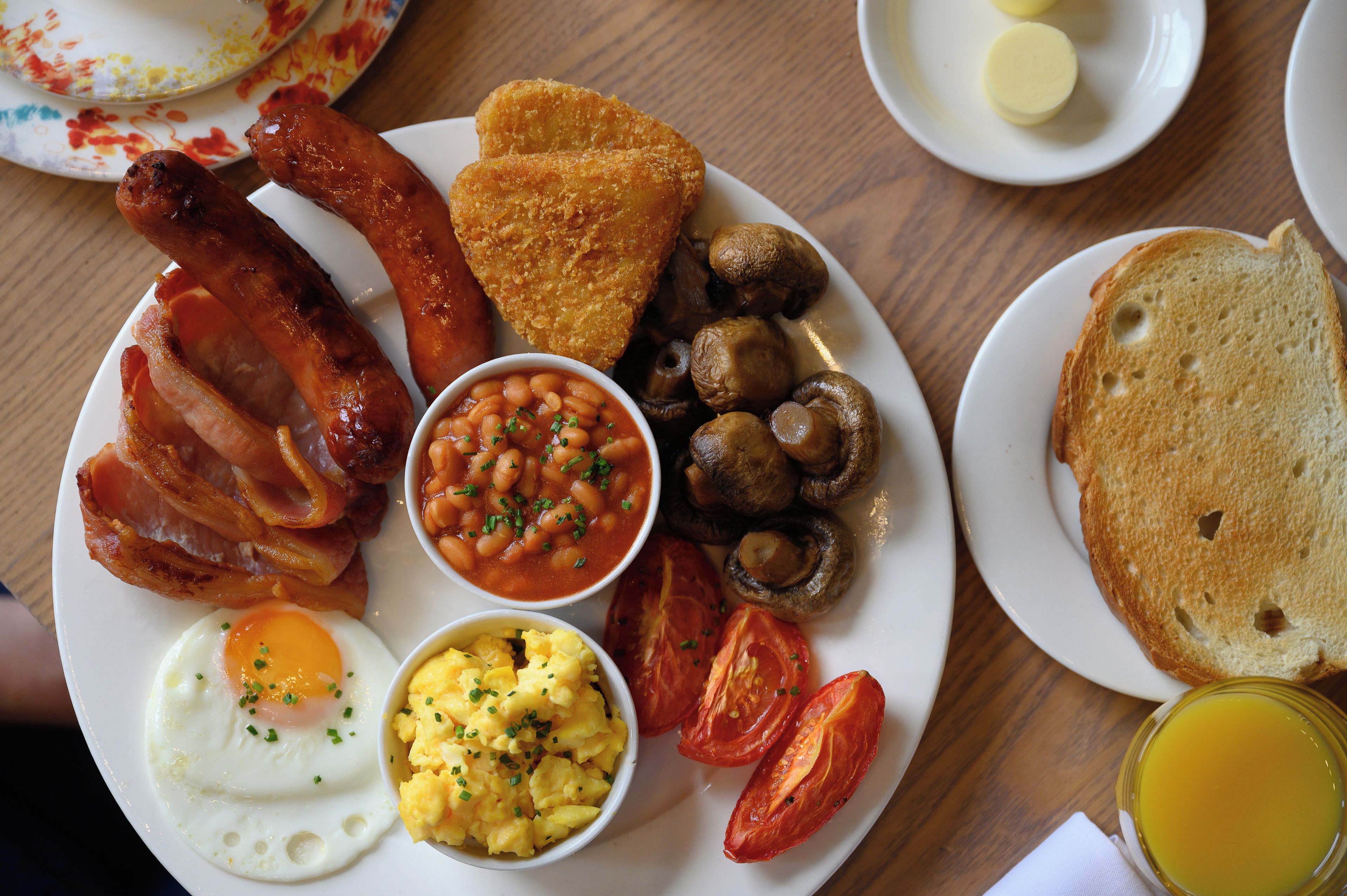 A breakfast plate with bacon, eggs, toast, mushrooms, beans, and tomatoes.