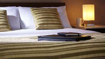 A neatly made bed with striped bedding, a bedside lamp, and a book on the nightstand.