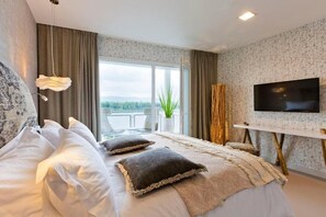 A modern bedroom with a large bed, a TV, and a balcony view. - Hotel de l'Abbaye (Grande-Rivière-Château)