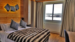 A bedroom with a bed, a view of a lake, and wooden walls. - Hotel de l'Abbaye (Grande-Rivière-Château)