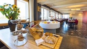 A breakfast buffet with various breads, pastries, and a vase of sunflowers. - Hotel de l'Abbaye (Grande-Rivière-Château)