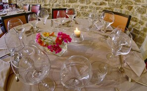 A dining table set with multiple wine glasses, a candle, and a floral centerpiece.