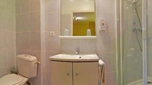 Een badkamer met toilet, wastafel, spiegel en een douchecabine van glas.