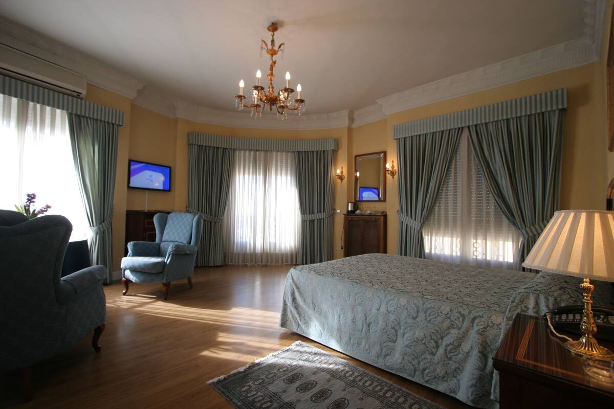Una camera d'albergo con un letto grande, una scrivania, una sedia, un televisore e tende.