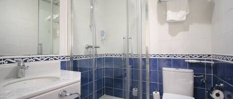 A bathroom with a glass-enclosed shower, a white sink, and a toilet.