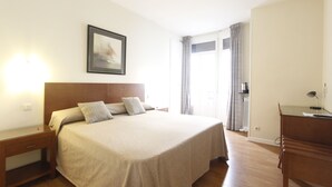 A hotel room with a large bed, a bedside table, a desk, and a window with curtains. - El Rincon de Gran Via (Madrid)