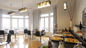 A dining area with a buffet, chairs, and a view of the city through large windows. - El Rincon de Gran Via (Madrid)