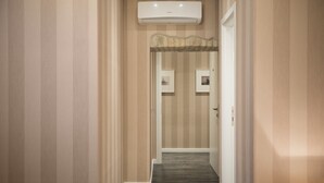 A hallway with striped wallpaper, a dark wooden floor, and a white door at the end. - San Pietro Suites (Rome)