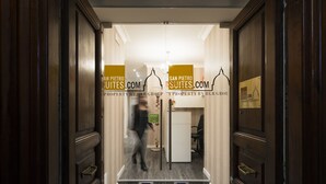 A hotel entrance with wooden doors and a sign indicating it's a property by HLR Group. - San Pietro Suites (Rome)