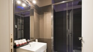 A modern bathroom with a large white sink, a glass shower enclosure, and a mirror above the sink. - San Pietro Suites (Rome)
