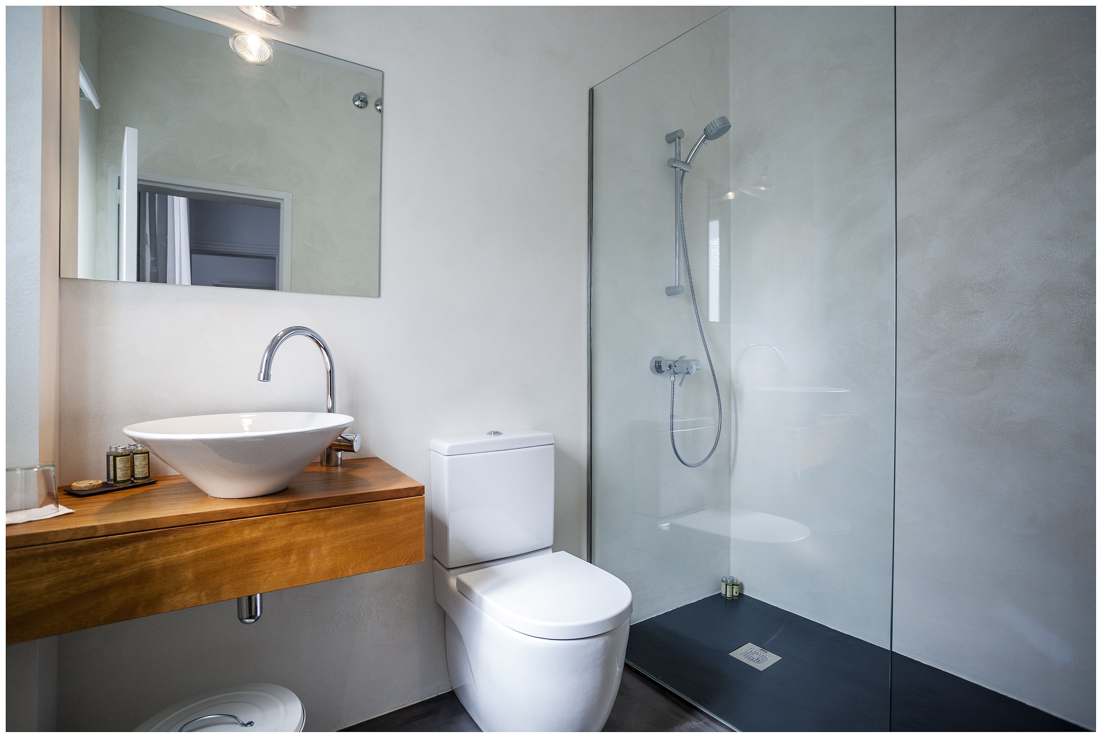 A modern bathroom with a white sink, wooden vanity, and a glass shower enclosure.