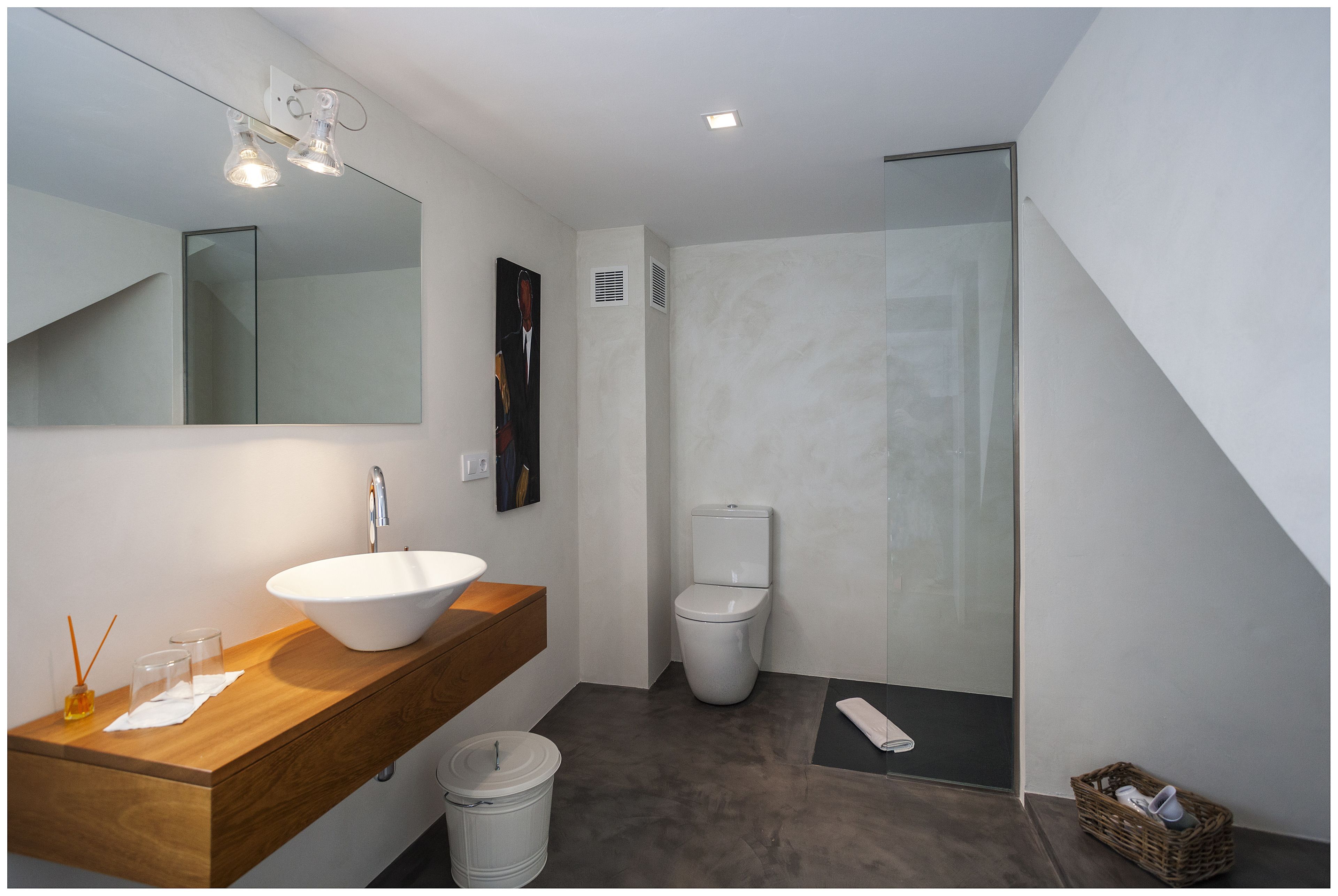 Une salle de bain moderne avec un meuble-lavabo en bois, un grand miroir, un lavabo blanc, des toilettes et un espace douche.