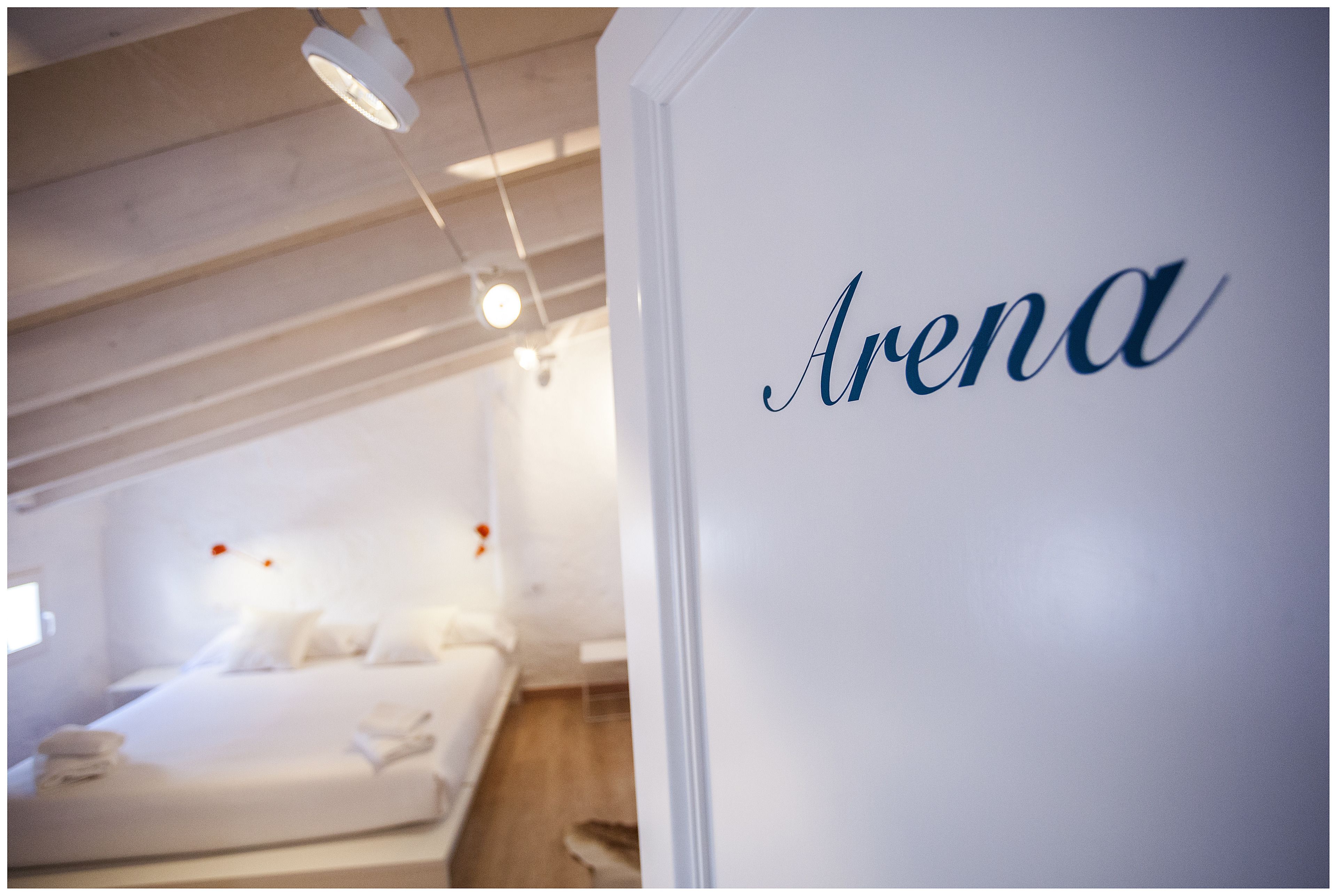 A hotel room with a bed, a nightstand, and a wall with the word "Arena" written on it.