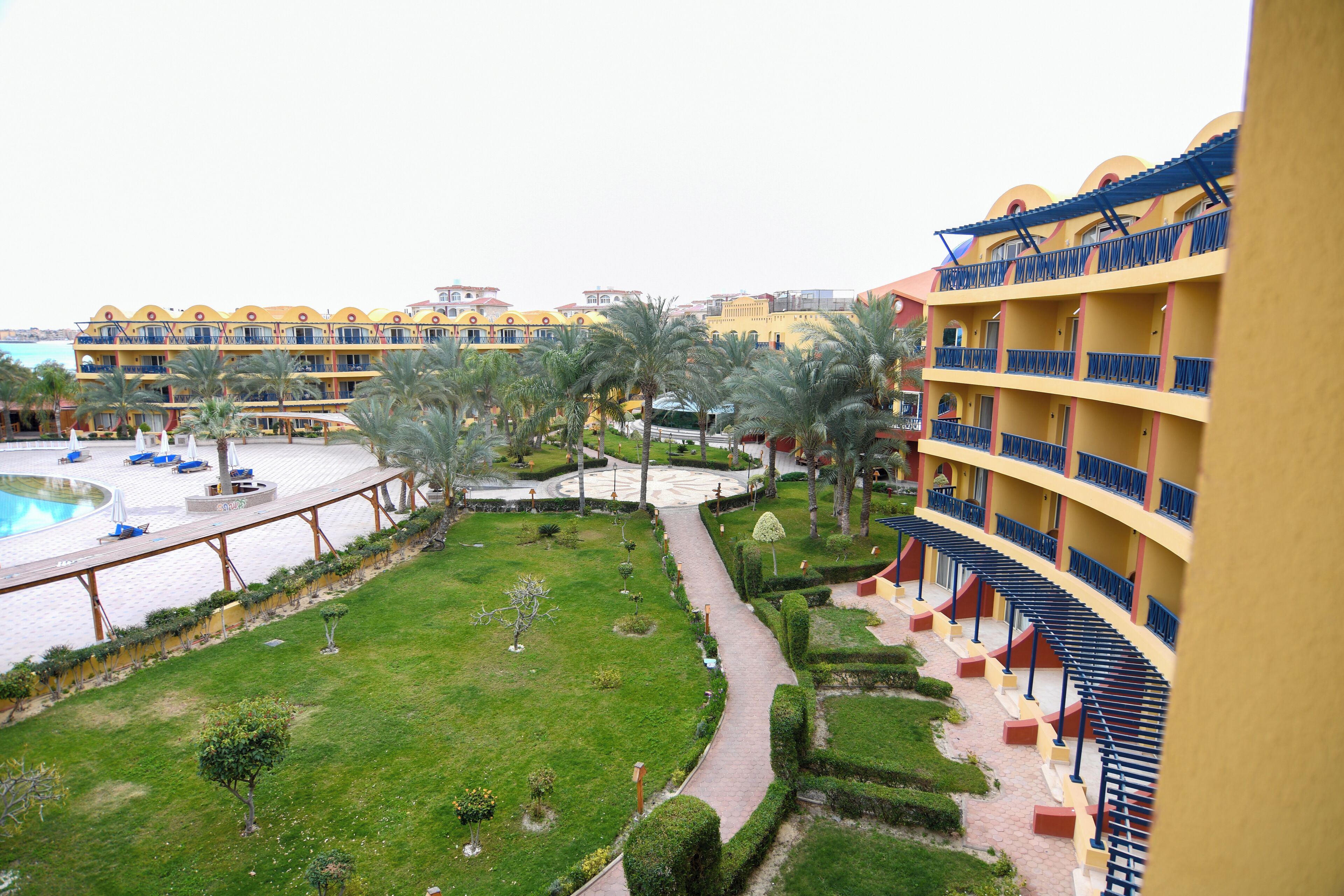 Un hotel con varios balcones, piscina y jardines bien cuidados.