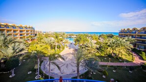 A resort with multiple buildings, a central pool, and palm trees. - Carols Beau Rivage Hotel (Marsa Matrouh)
