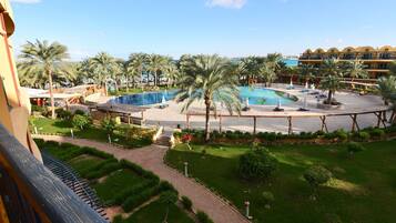 A resort with a large pool, palm trees, and a well-maintained garden.