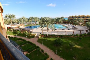 A resort with a large pool, palm trees, and a well-maintained garden.