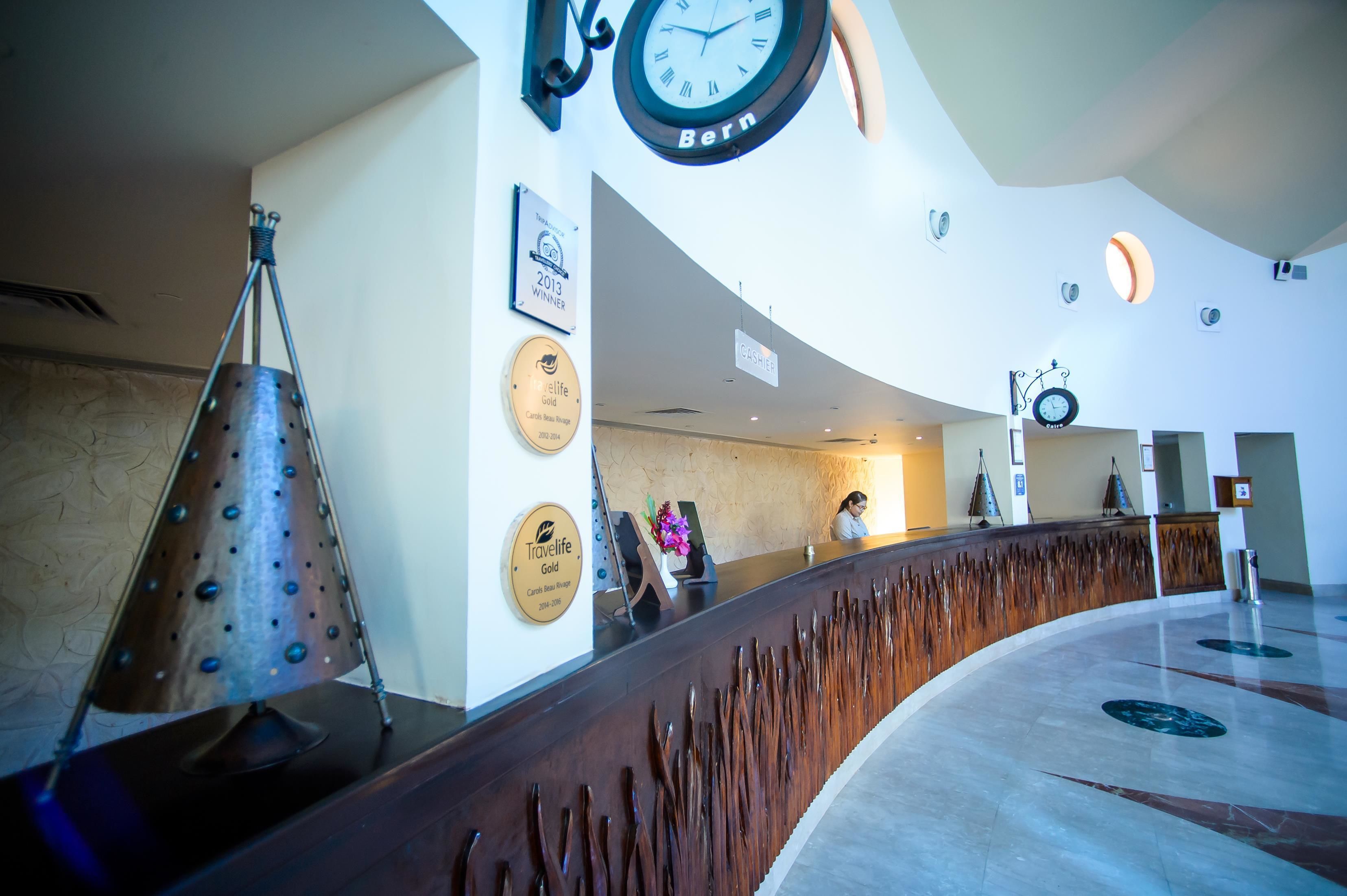 A reception area with a curved wooden counter, a clock, and several plaques on the wall.