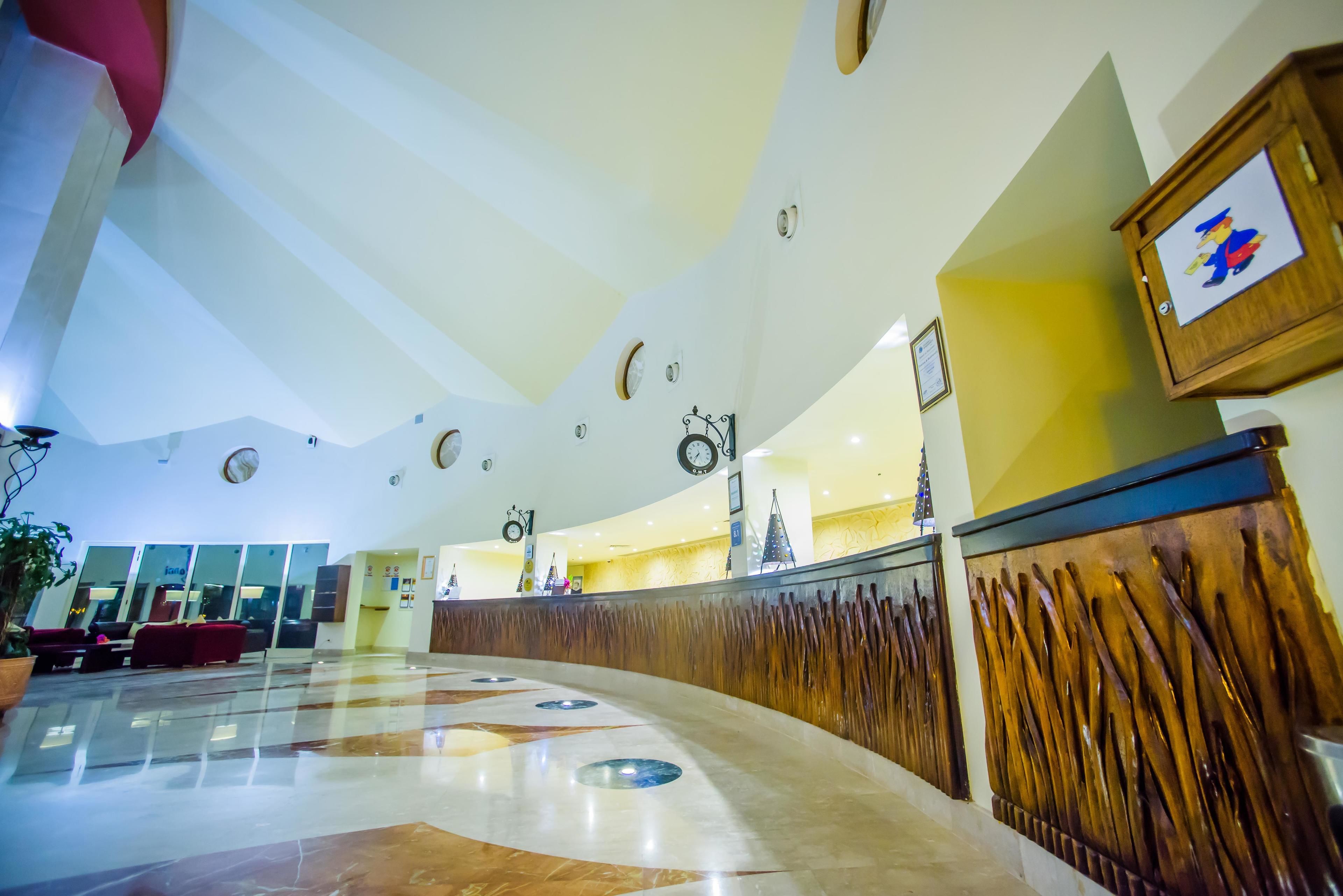 A hotel lobby with a curved reception desk, a clock, and a Christmas tree.