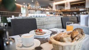 A breakfast setting with a plate of toast, strawberries, a glass of orange juice, and a cup of coffee on a table. - Hotel Burgaunerhof (Martello)