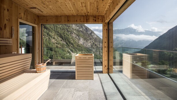 A wooden interior with a large window offering a mountain view. - Hotel Burgaunerhof (Martello)