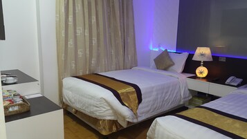 A hotel room with a bed, bedside table, lamp, and a small table with a basket.